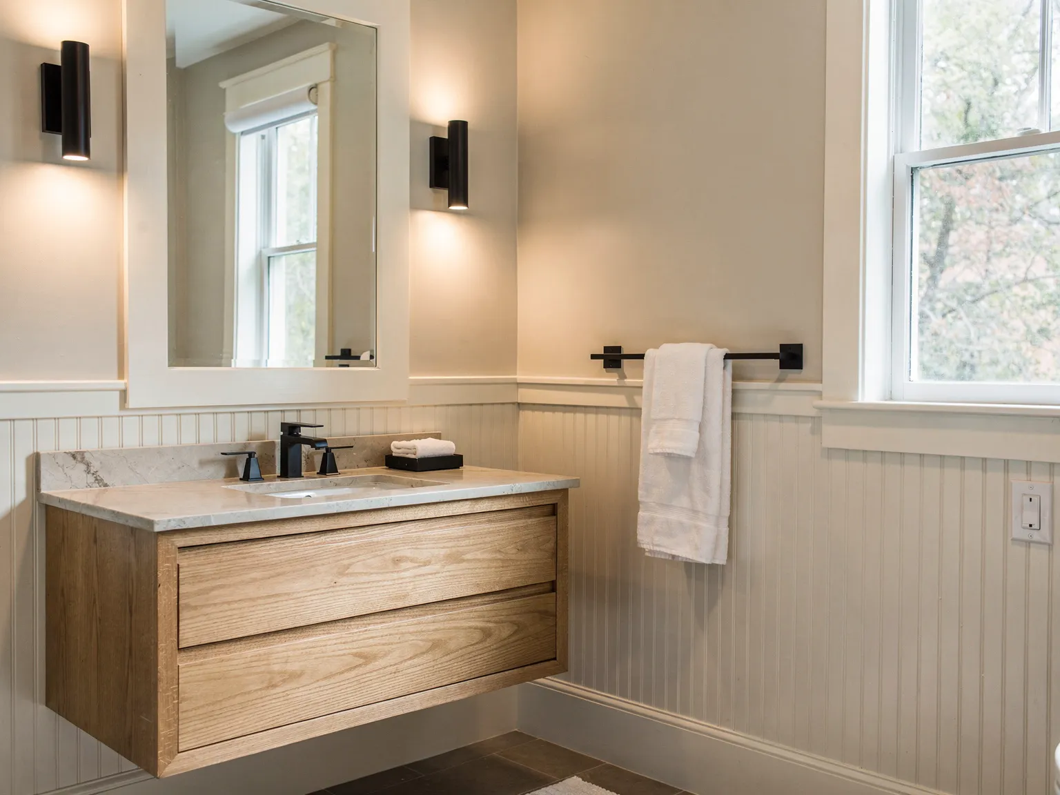 Bathroom with custom cabinetry, wainscoting, and trim